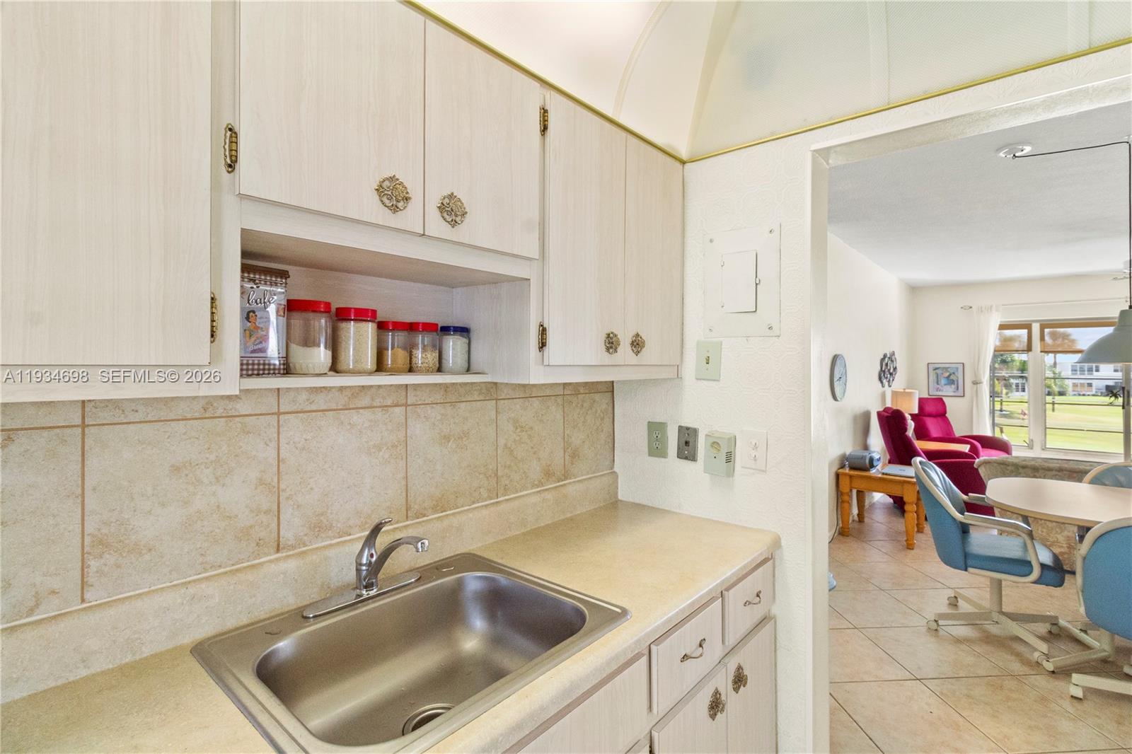 A kitchen sink and cabinets are shown with an adjacent view into a living area — 2850 W Golf Blvd # 211, Pompano Beach FL 33064, POMPANO BEACH, FL