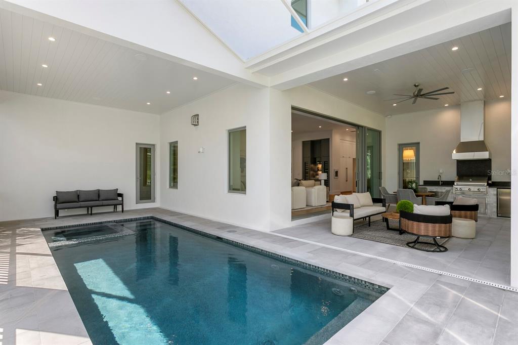 A covered outdoor patio features a swimming pool, lounge seating, and an integrated kitchen area — 423 S ROYAL POINCIANA DRIVE, TAMPA, FL