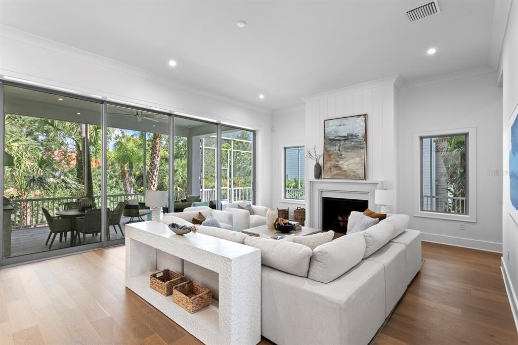 A bright living room features a white sectional sofa, fireplace, and large sliding glass doors — 423 S ROYAL POINCIANA DRIVE, TAMPA, FL