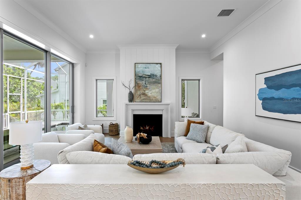 A bright living room features a fireplace, white sectional sofa, and large sliding glass doors — 423 S ROYAL POINCIANA DRIVE, TAMPA, FL