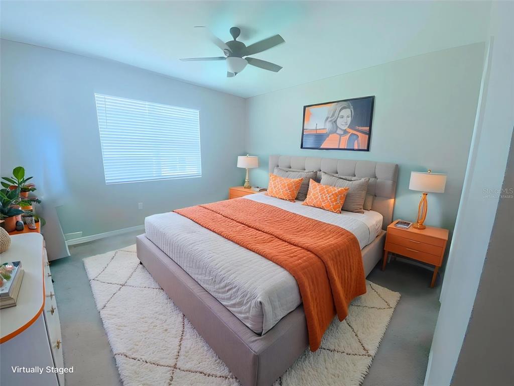 A bedroom features a bed with orange bedding, two nightstands, and a ceiling fan — 2673 SPIDER LILY COURT, CLERMONT, FL