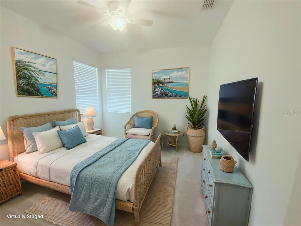 A bedroom features a wicker bed frame, blue bedding, a dresser, and a wall-mounted television — 2673 SPIDER LILY COURT, CLERMONT, FL