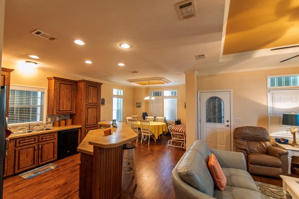 An open-concept kitchen, dining area, and living room feature wood cabinets and hardwood flooring — 31 COPENHAGEN AVENUE, PUNTA GORDA, FL