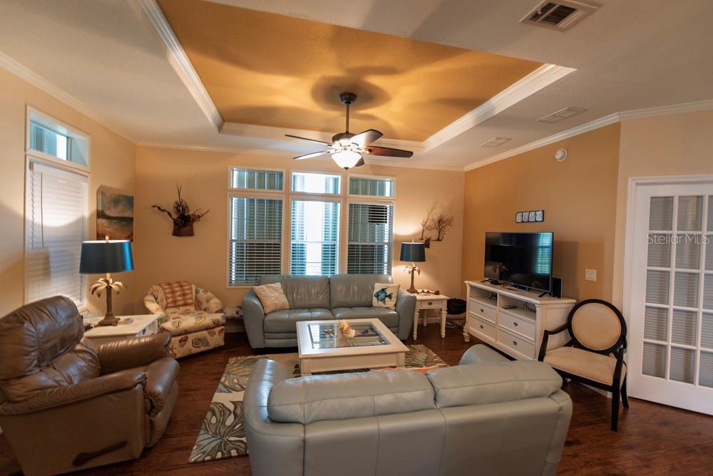 A living room features a tray ceiling, a ceiling fan, and light blue leather furniture — 31 COPENHAGEN AVENUE, PUNTA GORDA, FL