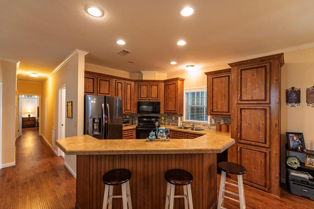 A kitchen with wood cabinets, a breakfast bar with stools, and stainless steel appliances — 31 COPENHAGEN AVENUE, PUNTA GORDA, FL