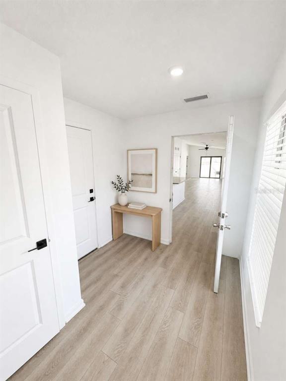 A bright entryway features light wood-look flooring, a white door, and a small wooden console table — 5668 FLOTILLA AVENUE, TAMPA, FL