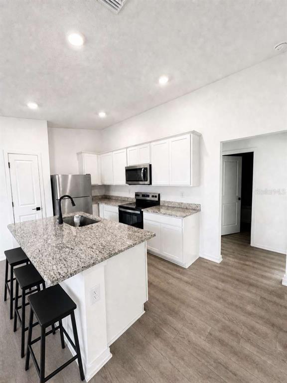 A kitchen features white cabinets, granite countertops, stainless steel appliances, and a central island — 5668 FLOTILLA AVENUE, TAMPA, FL