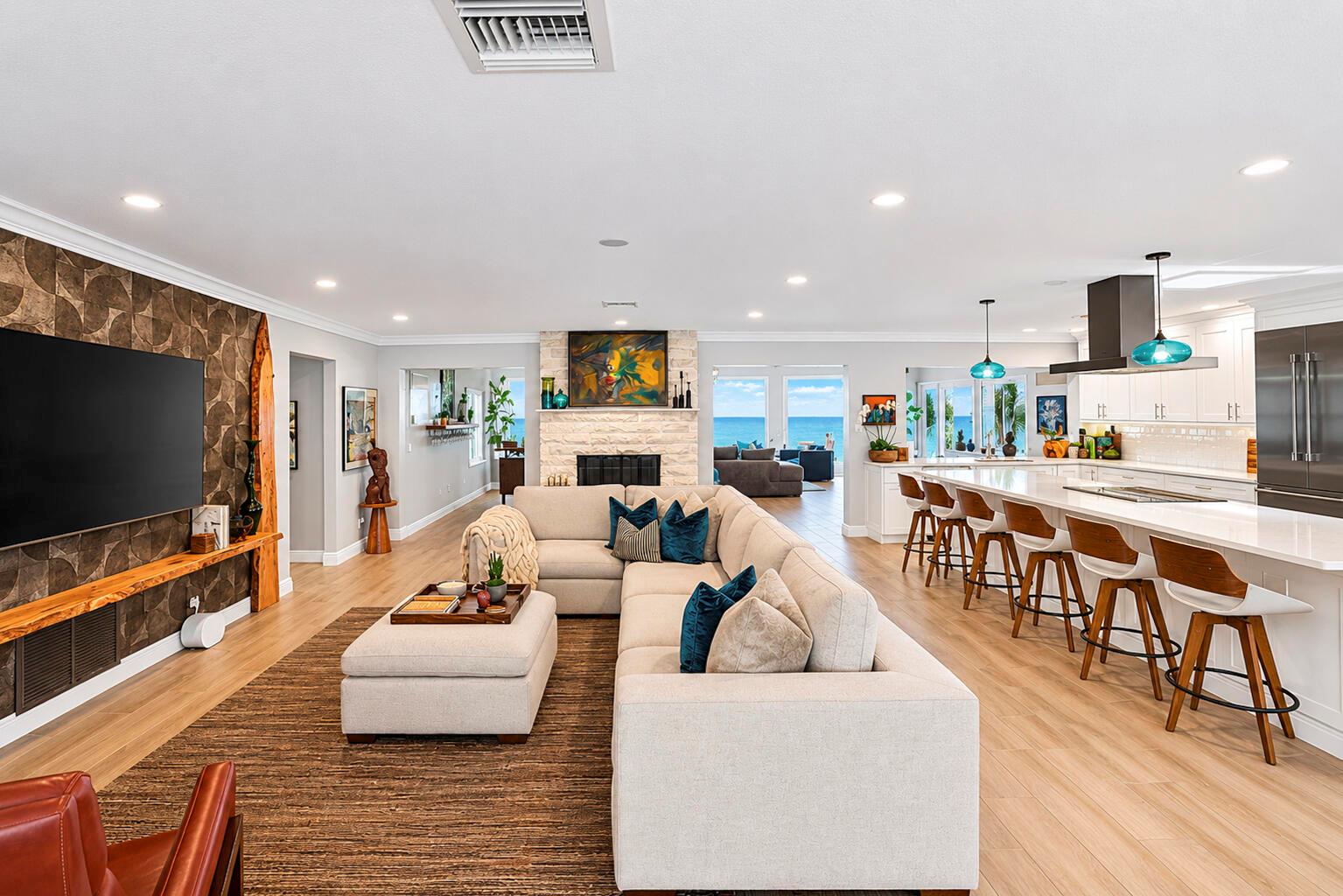 An open-concept living room and kitchen featuring a large sectional, fireplace, and ocean views — VERO BEACH, FL