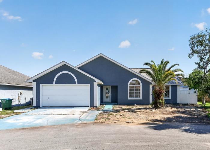 A blue single-story house with a two-car garage and a palm tree in the yard — 104 SEASHELL COURT, PANAMA CITY BEACH, FL
