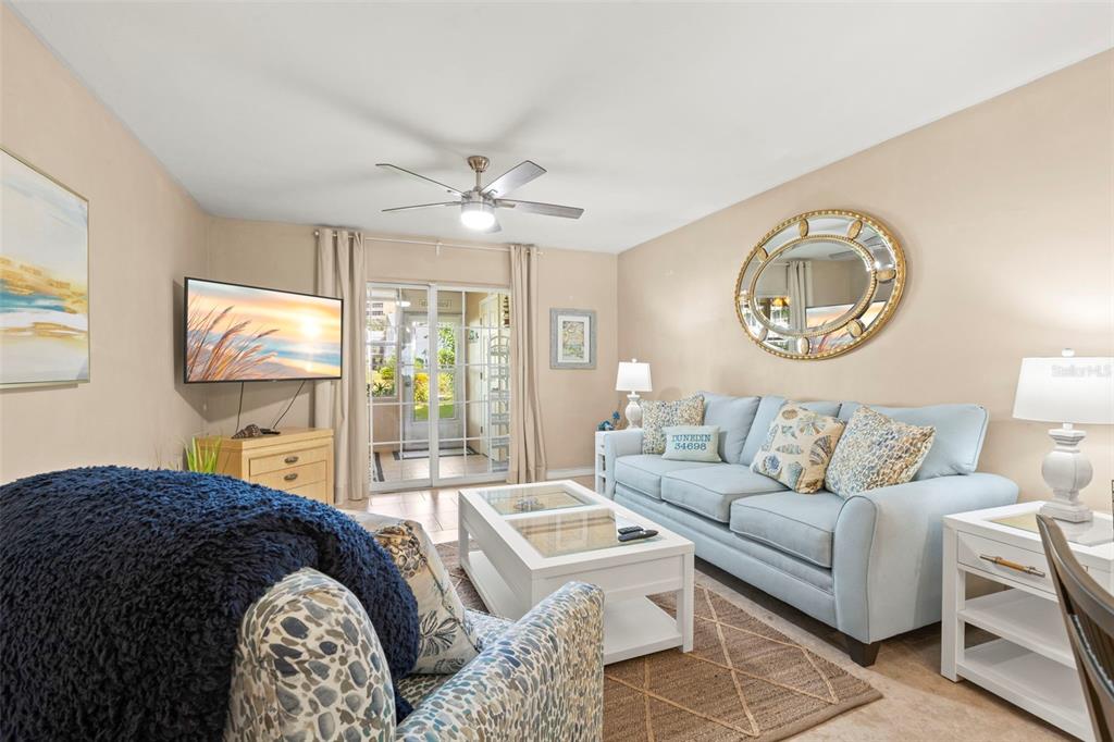 A living room features a light blue sofa, a coffee table, and a ceiling fan — 400 GLENNES LANE UNIT 107, DUNEDIN, FL