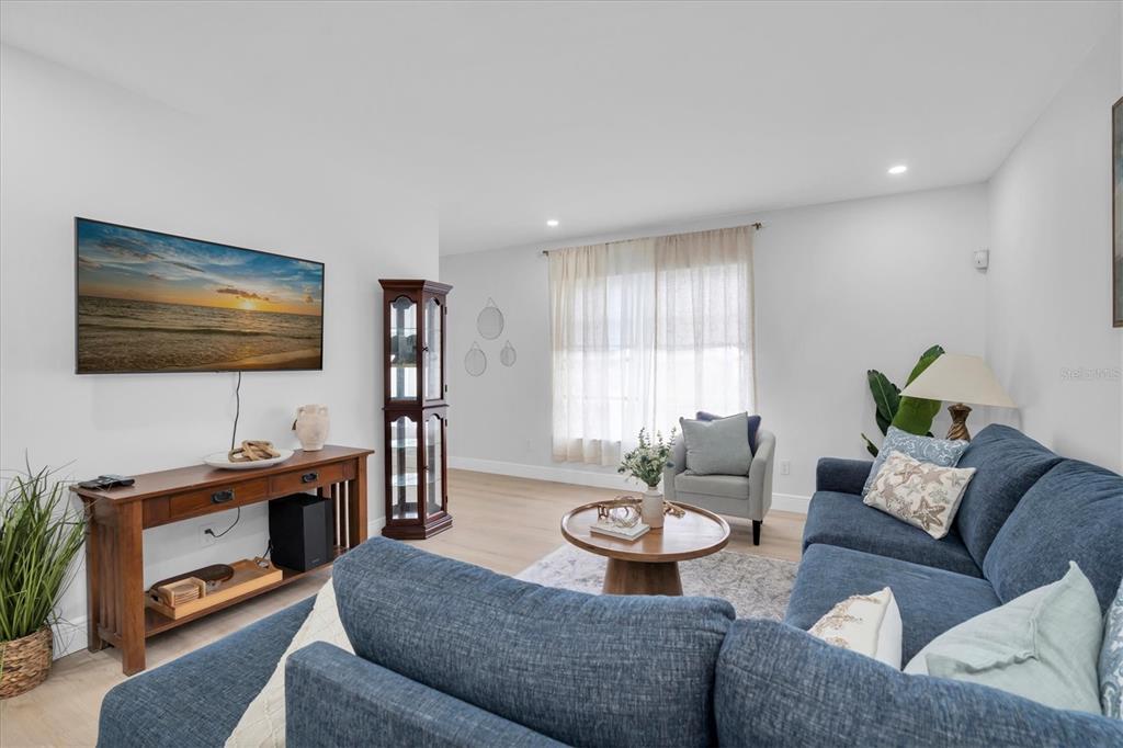 A living room features a blue sectional sofa, a wooden media console, and a display cabinet — 8236 BRENTWOOD ROAD, SEMINOLE, FL