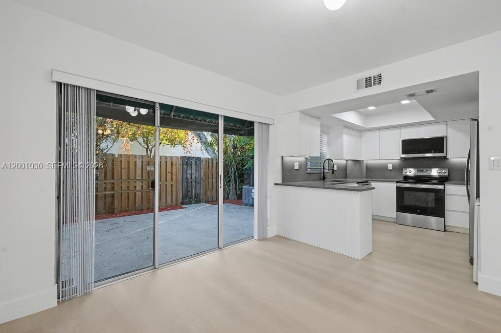 A modern kitchen with white cabinets and a patio view through sliding glass doors — 12224 SW 52nd Pl, Cooper City FL 33330, COOPER CITY, FL