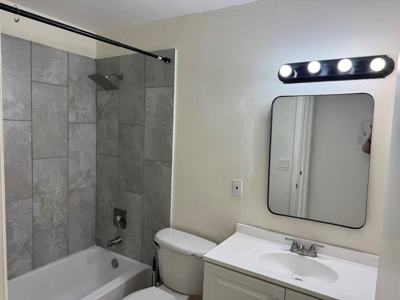 A bathroom features a gray tiled shower surround, a white vanity, and a black-framed mirror — 1227 SW 46th Avenue SW # 301, Pompano Beach FL 33069, POMPANO BEACH, FL