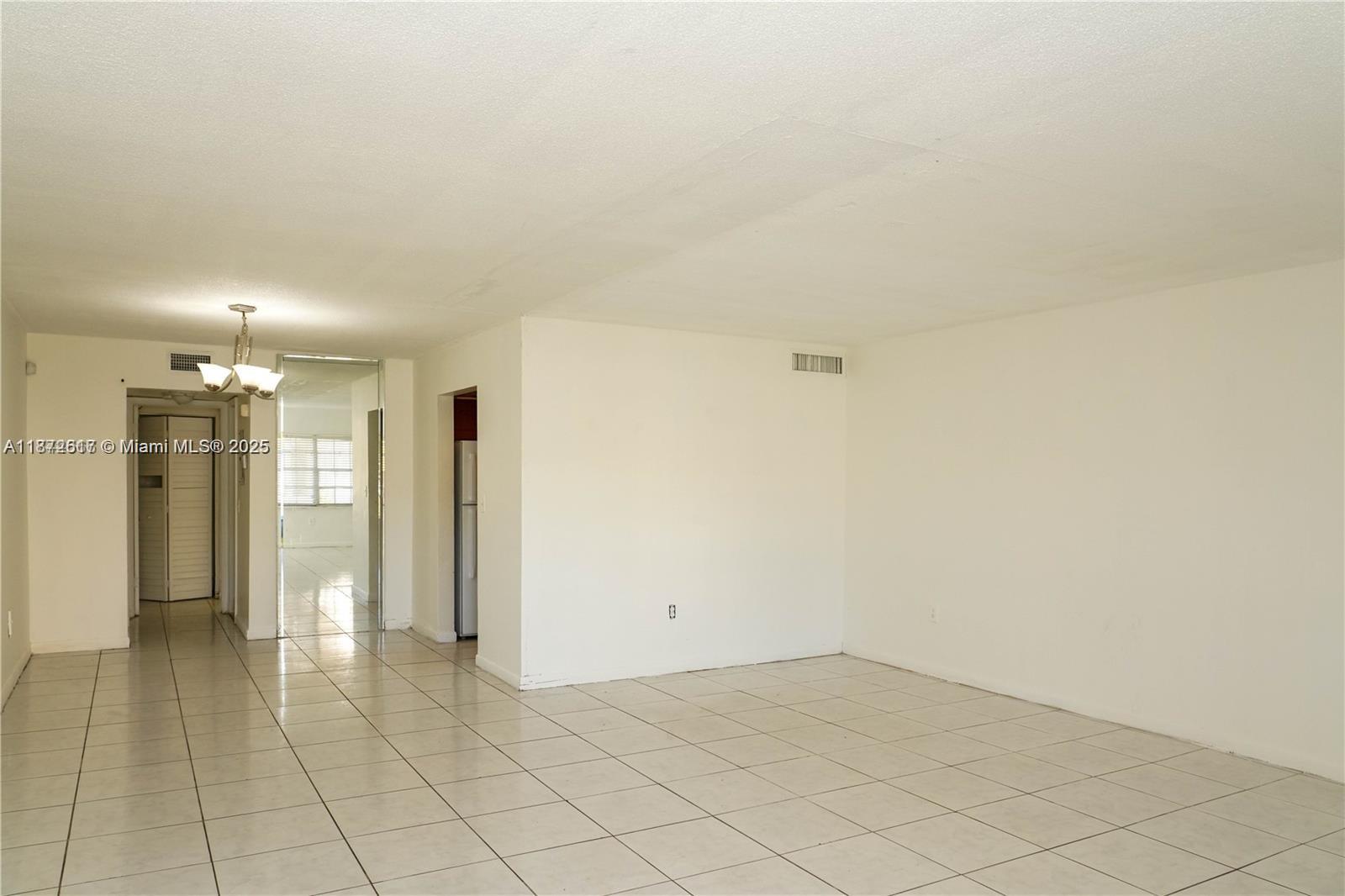 An empty room with white walls and light-colored tile flooring features a ceiling light fixture — 11855 NE 19th Dr # 10, North Miami FL 33181, NORTH MIAMI, FL
