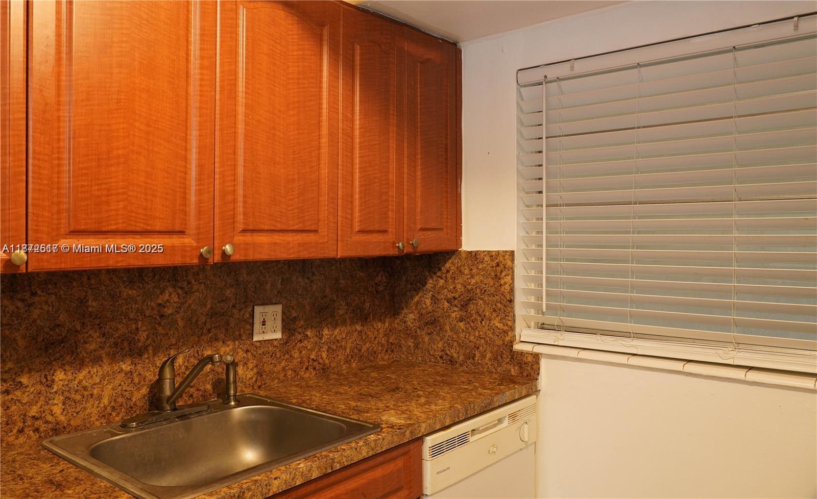 A kitchen features wood cabinets, a granite countertop, a stainless steel sink, and a dishwasher — 11855 NE 19th Dr # 10, North Miami FL 33181, NORTH MIAMI, FL
