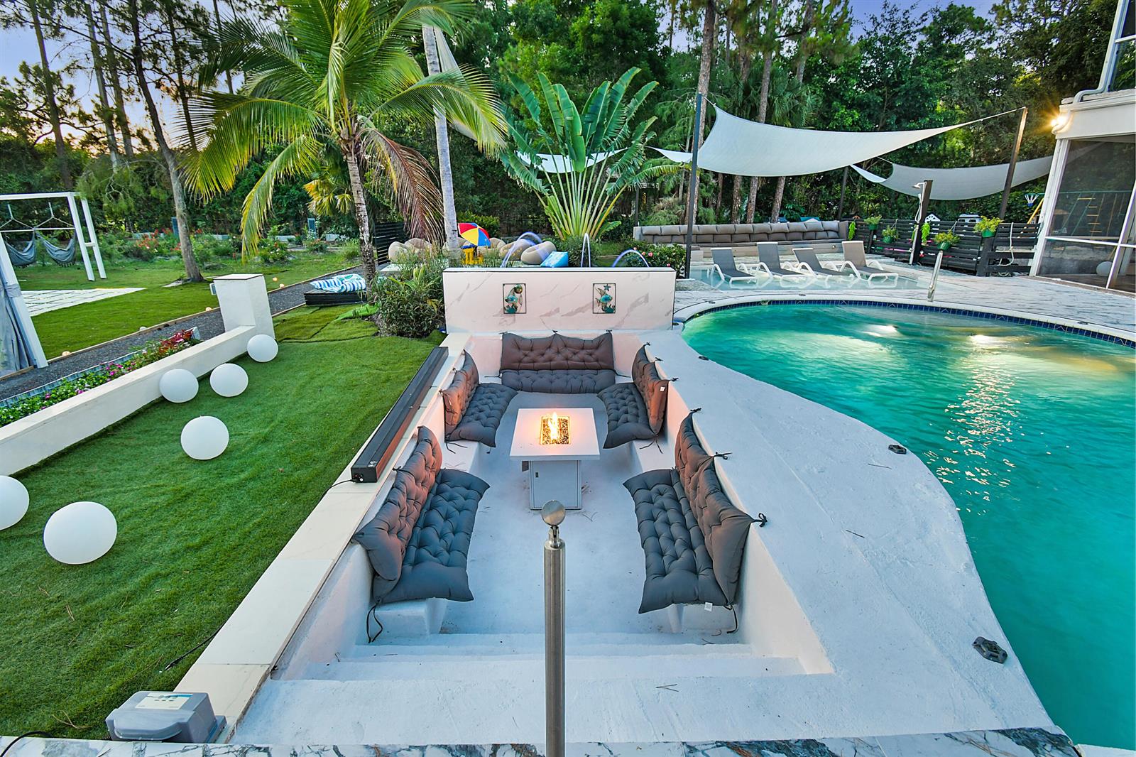 A sunken outdoor seating area with a fire pit sits beside a swimming pool — 377 Squire Drive, Wellington FL 33414, WELLINGTON, FL