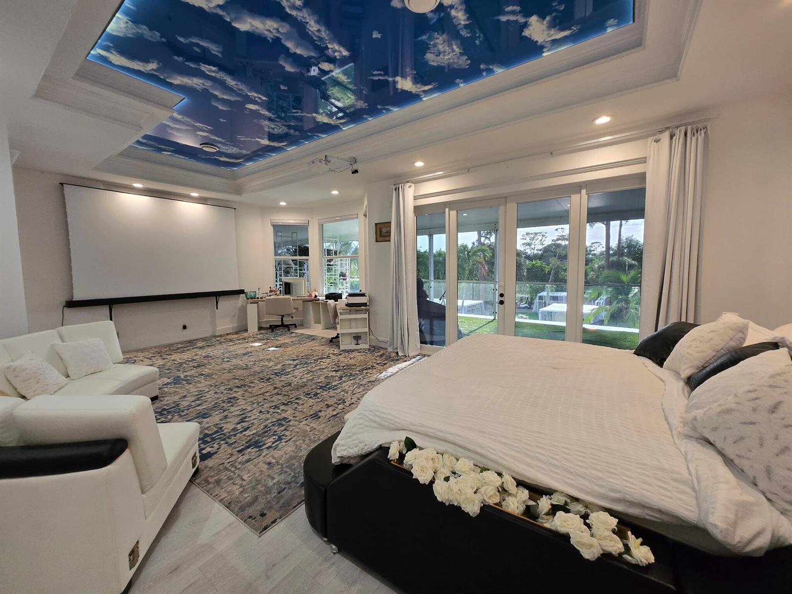 A bedroom features a cloud-painted ceiling, a projector screen, a large bed, and glass doors — 377 Squire Drive, Wellington FL 33414, WELLINGTON, FL