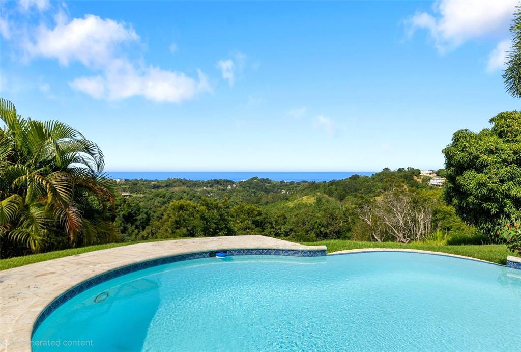 A curved swimming pool overlooks a lush green landscape and the distant ocean — VILLA DE SUENOS SECTOR KOREA, RINCON, PR