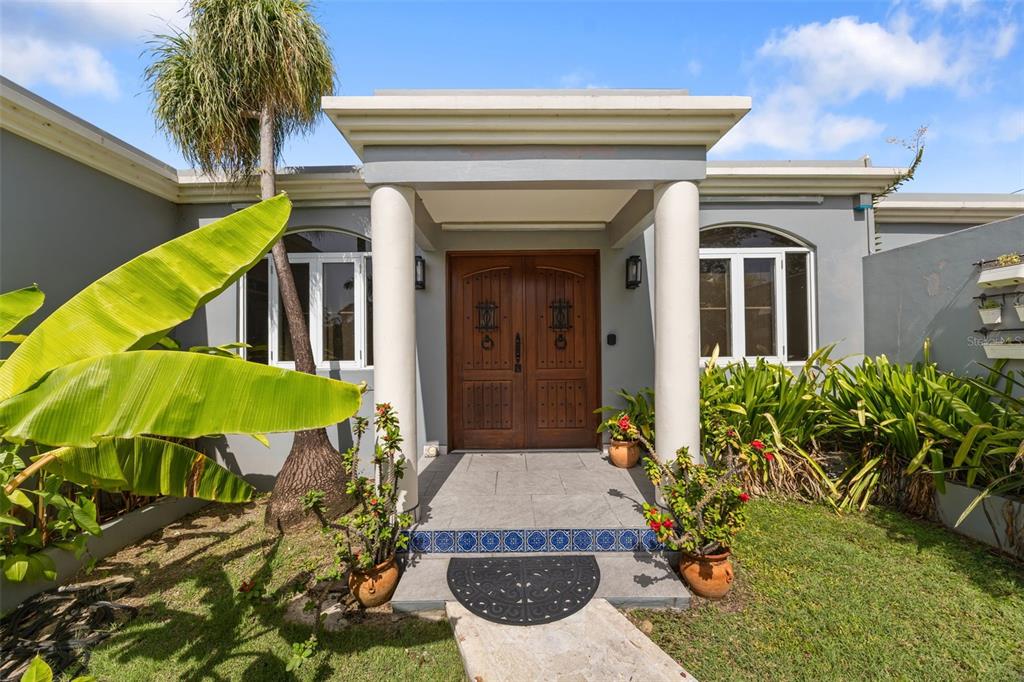 The front entrance features a wooden double door framed by two white columns — VILLA DE SUENOS SECTOR KOREA, RINCON, PR