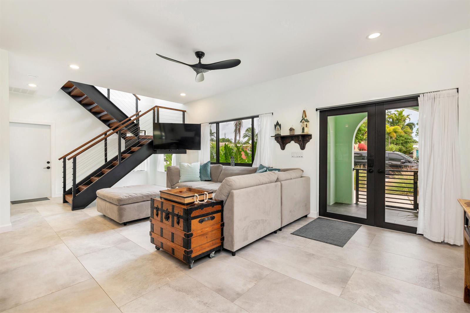 A living room features a sectional sofa, a wooden trunk, and a modern metal staircase — 127 Auburn Drive, FL 33460, FL