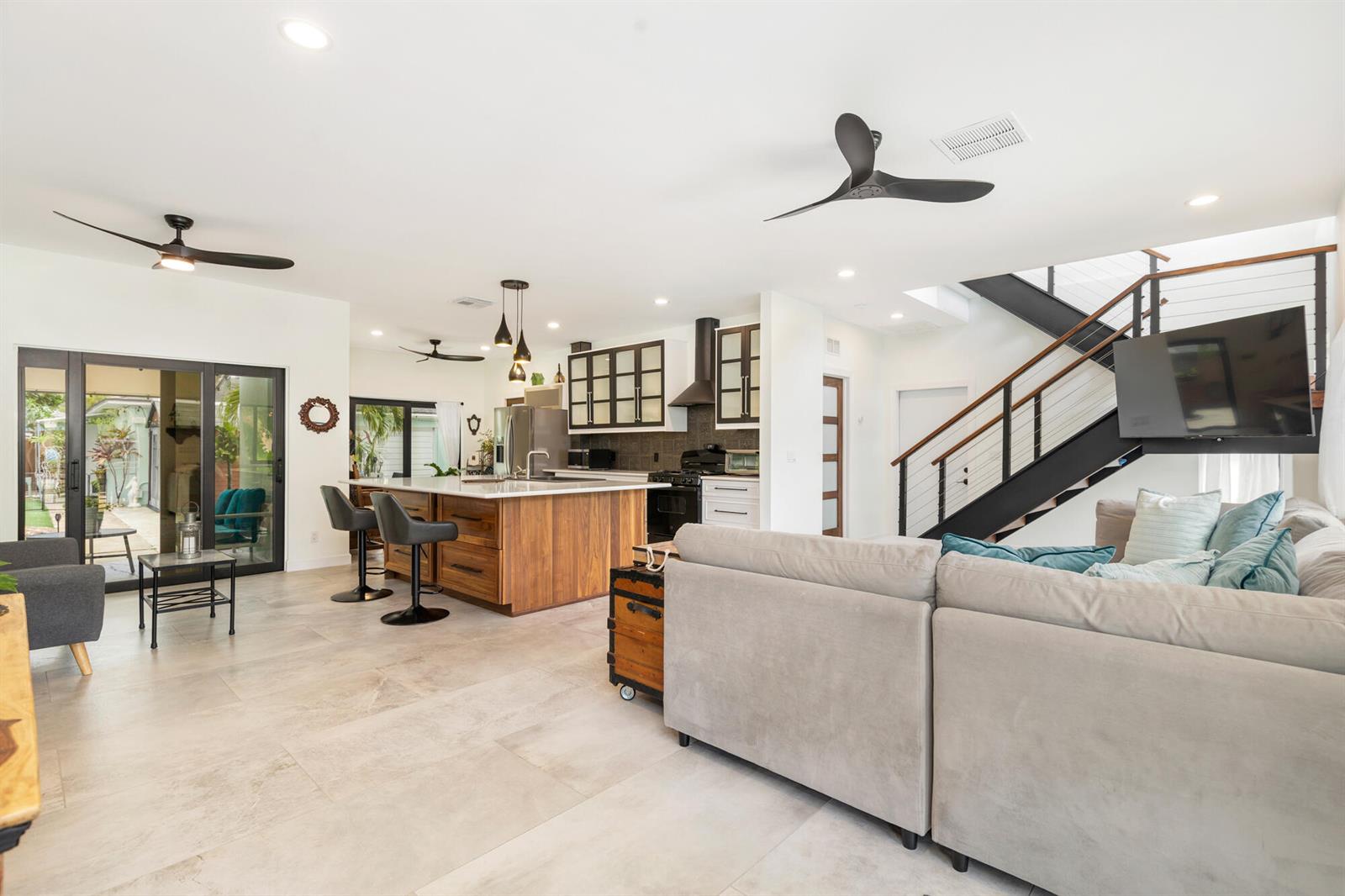 An open-concept living room and kitchen with a large island, staircase, and tile flooring — 127 Auburn Drive, FL 33460, FL