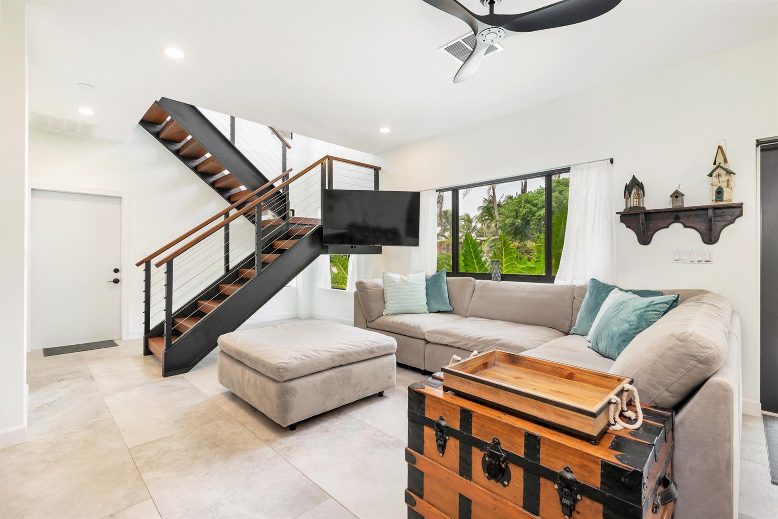 A living room features a sectional sofa, a large ottoman, and a modern floating staircase — 127 Auburn Drive, FL 33460, FL