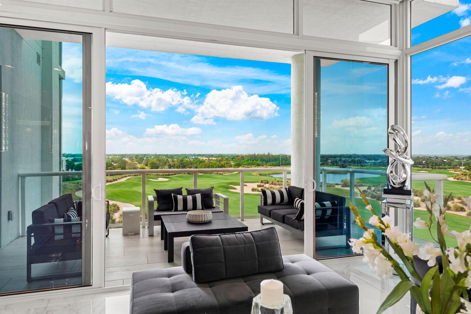 A balcony with outdoor seating overlooks a golf course through large glass sliding doors — 20155 Boca West Drive # B804, Boca Raton FL 33434, BOCA RATON, FL
