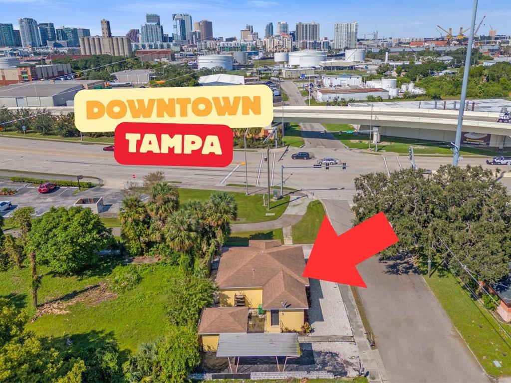 An aerial view shows a yellow house with a brown roof near a city skyline — 309 N 22ND STREET, TAMPA, FL