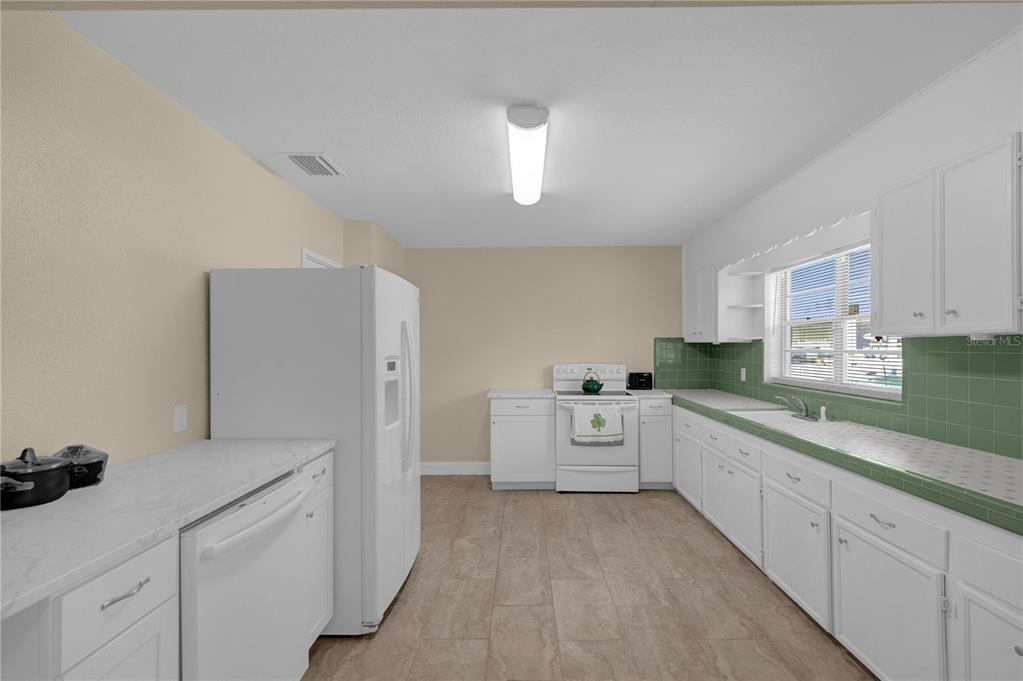 A kitchen features white cabinets, green tiled countertops, a white refrigerator, and a white stove — 309 N 22ND STREET, TAMPA, FL