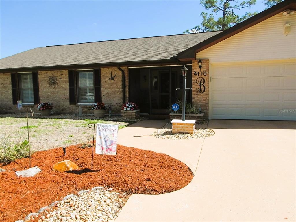 A single-story brick house features a garage, a front porch, and a landscaped yard — 4110 ALLURE LANE, NORTH PORT, FL