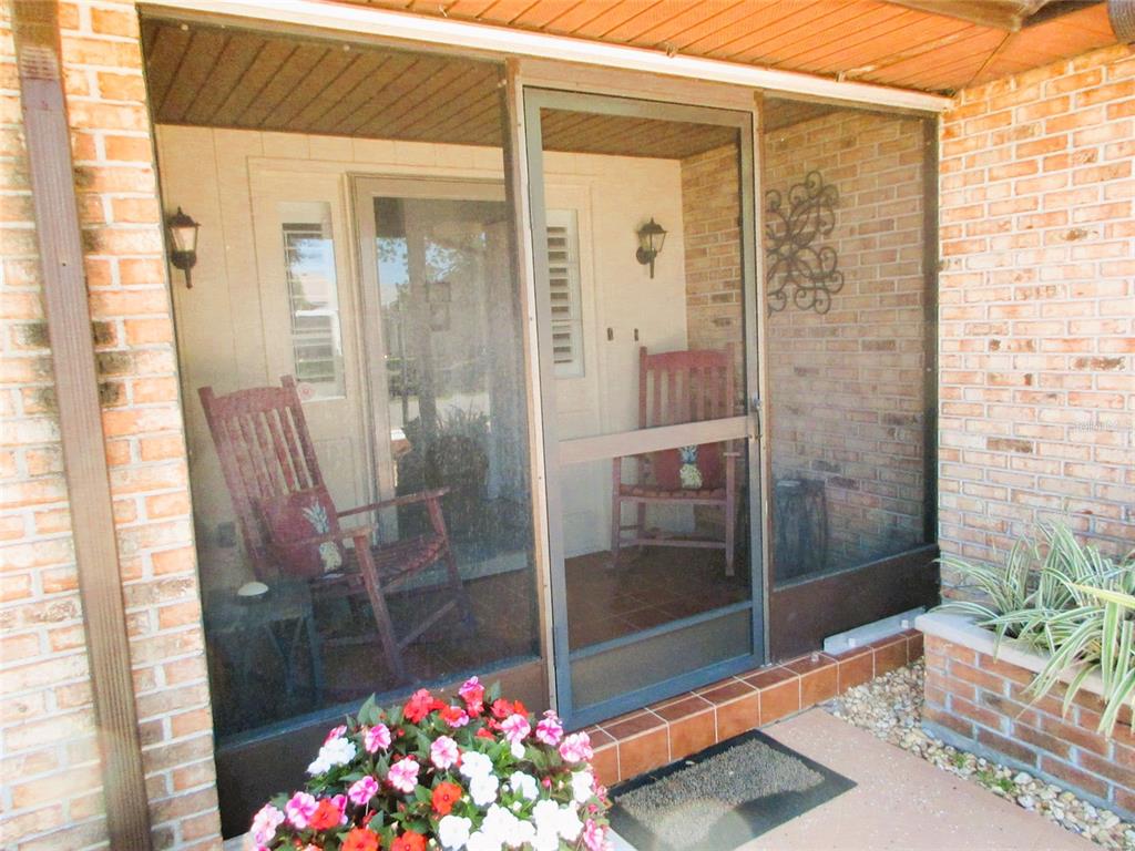 A screened-in porch features brick walls, two wooden rocking chairs, and a central screen door — 4110 ALLURE LANE, NORTH PORT, FL