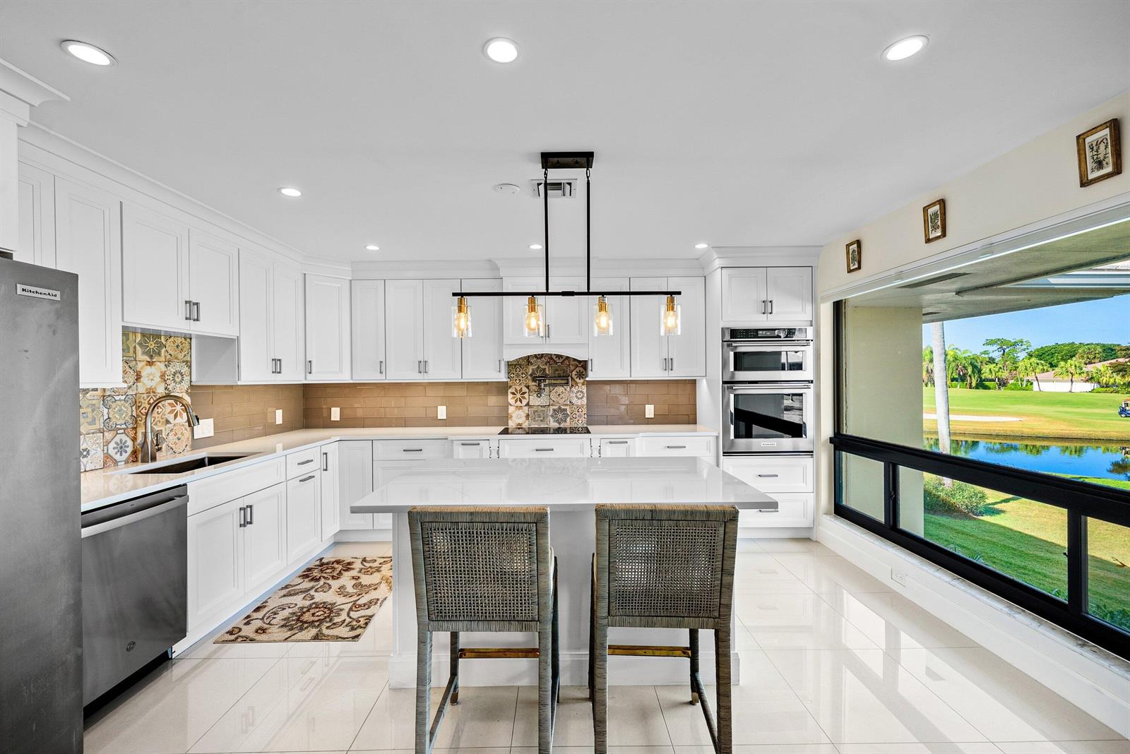 A white kitchen features a center island, stainless appliances, and a large window overlooking water — 3637 Quail Ridge Drive # A, Boynton Beach FL 33436, BOYNTON BEACH, FL