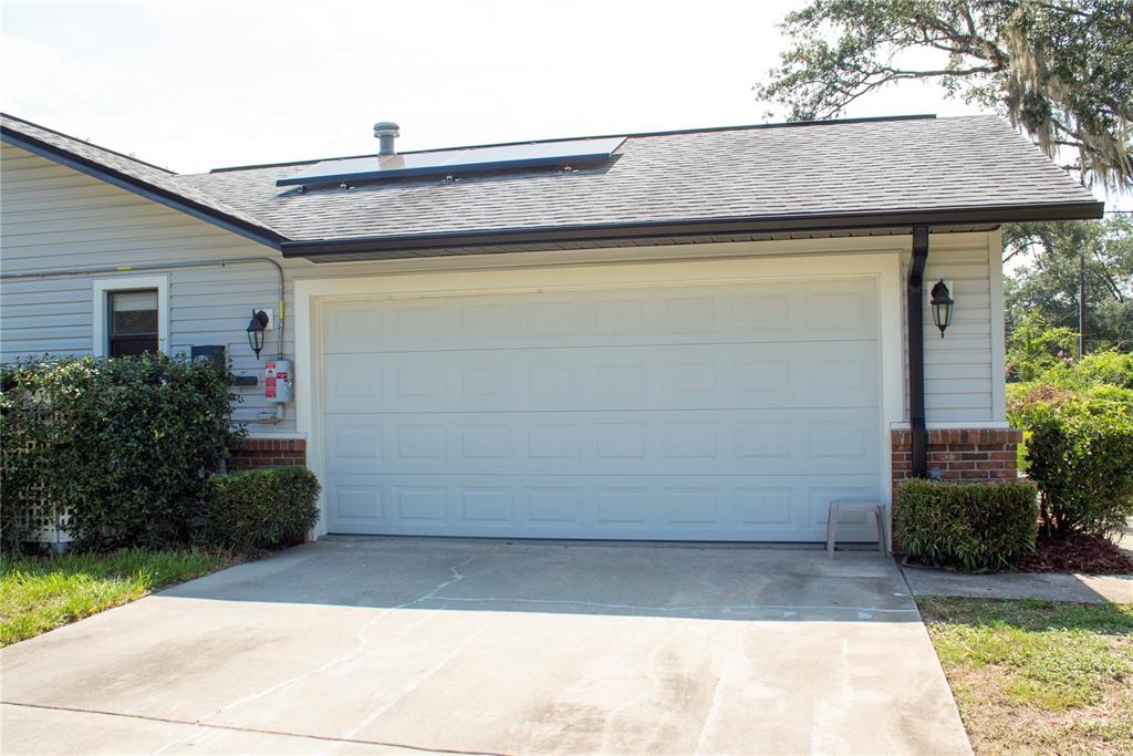 A white garage door is set into a house exterior with gray siding and brick — 5245 E FORT KING STREET STREET, OCALA, FL