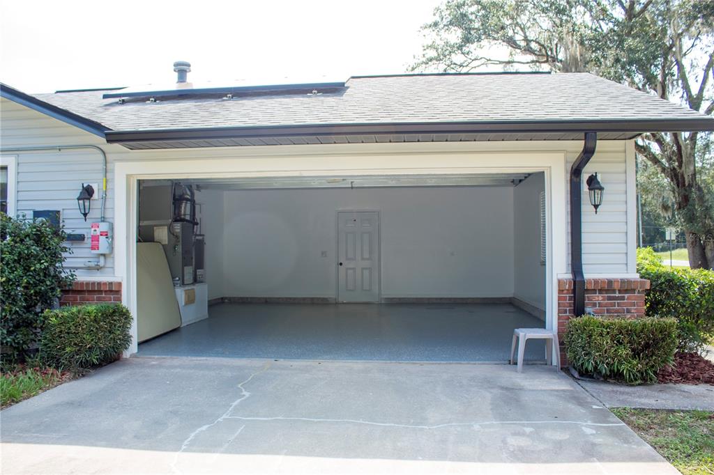 An open two-car garage with a concrete floor, a rear entry door, and exposed HVAC equipment — 5245 E FORT KING STREET STREET, OCALA, FL