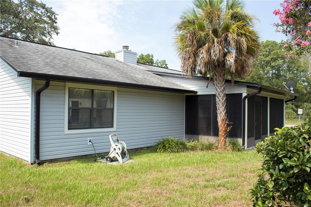 A light gray vinyl-sided house features a screened-in porch, a palm tree, and a lawn — 5245 E FORT KING STREET STREET, OCALA, FL