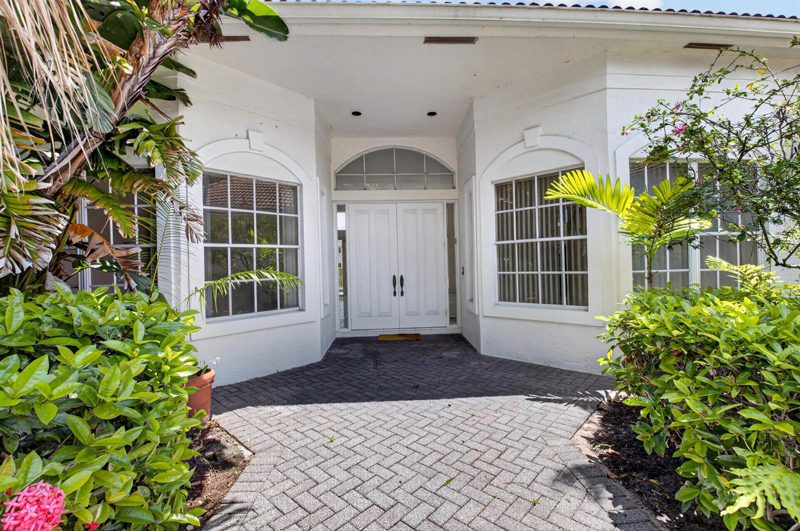 A white house exterior features a double front door, arched windows, and a paved walkway — 5768 Harrington Way, Boca Raton FL 33496, BOCA RATON, FL