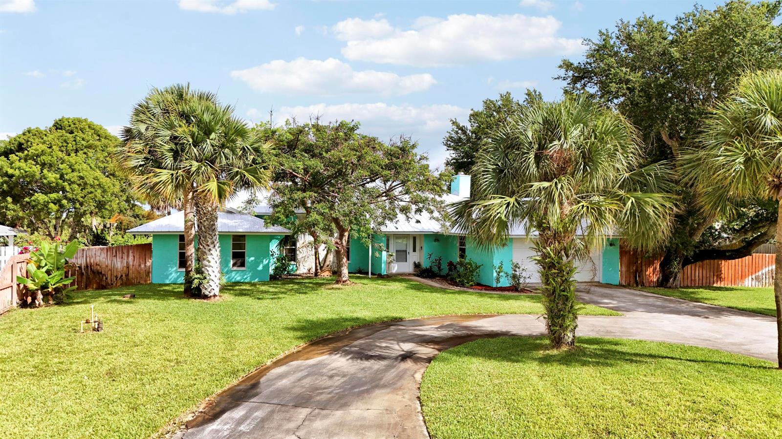 A turquoise single-story house with a white roof and a curved driveway sits on grass — 12744 Refuge Lane, Jensen Beach FL 34957, JENSEN BEACH, FL