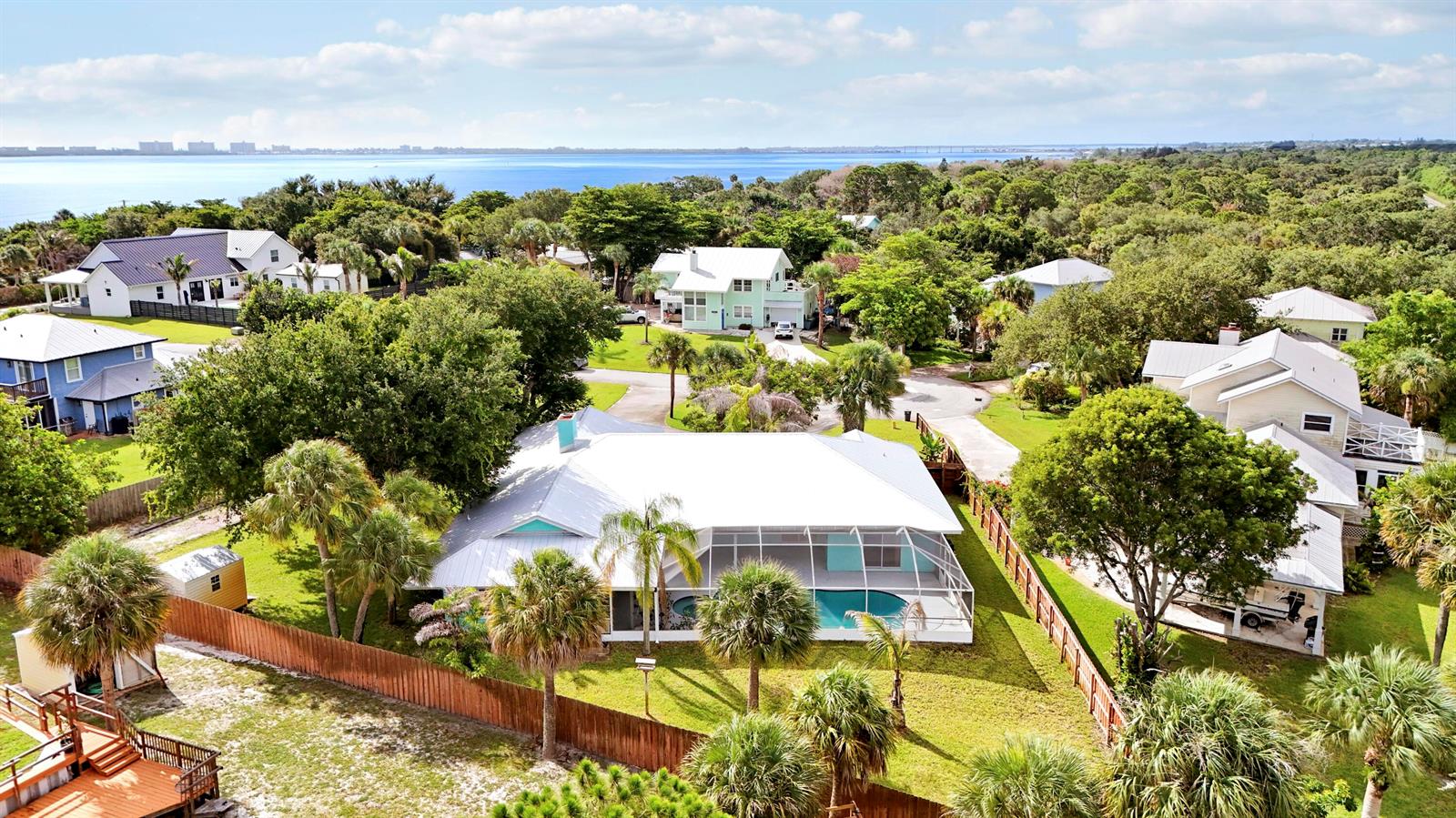 An aerial view shows a house with a white roof, pool enclosure, and surrounding trees — 12744 Refuge Lane, Jensen Beach FL 34957, JENSEN BEACH, FL