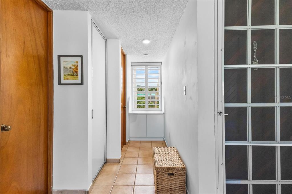 A hallway with tile floors, a white storage cabinet, and a window with shutters — 2306 CASA DEL MAR UNIT 2306, RIO GRANDE, PR