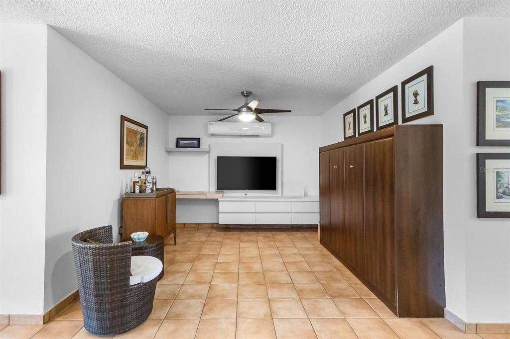 A living room features a wall-mounted television, a large wooden cabinet, and tile flooring — 2306 CASA DEL MAR UNIT 2306, RIO GRANDE, PR
