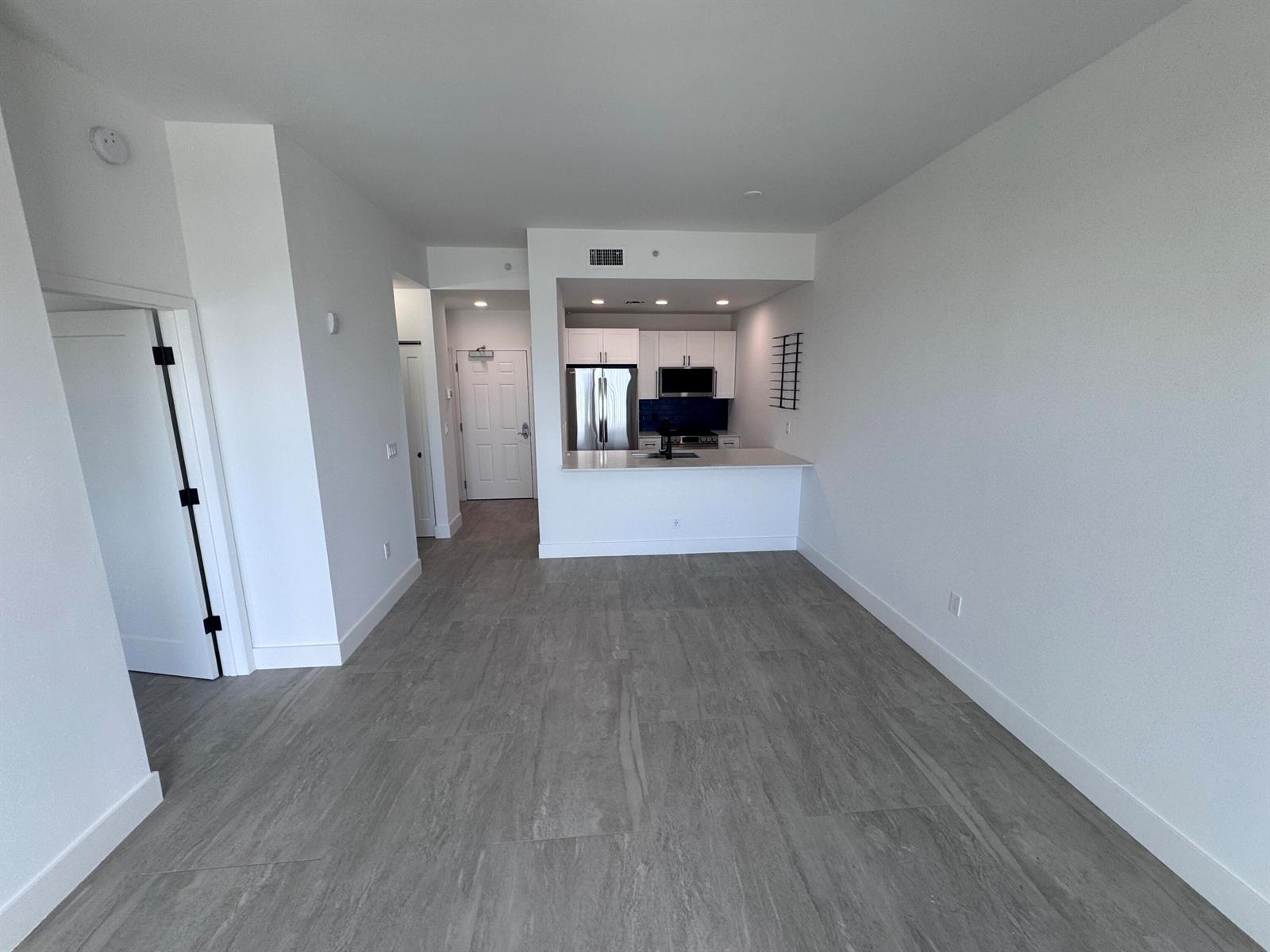 An open-concept living area features gray tile flooring, white walls, and a kitchen with white cabinetry — 511 Lucerne Avenue # 611, FL 33460, FL
