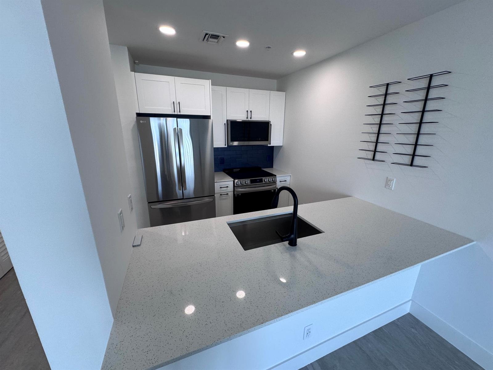 A kitchen features white cabinets, stainless steel appliances, a quartz countertop, and a black faucet — 511 Lucerne Avenue # 611, FL 33460, FL