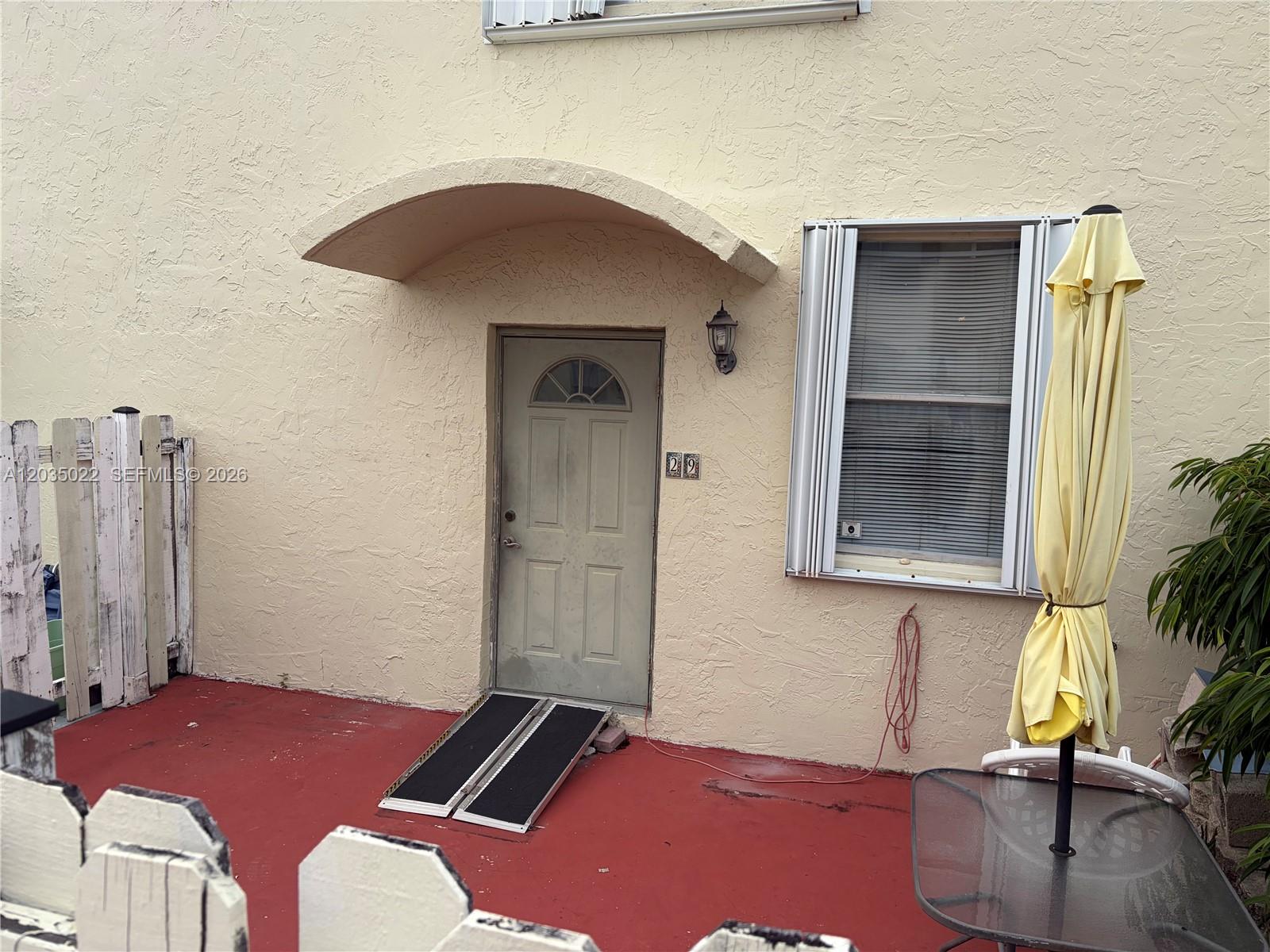 A beige exterior wall features a front door with a ramp and a window — 1655 NE 115th St # 29B, Miami FL 33181, MIAMI, FL