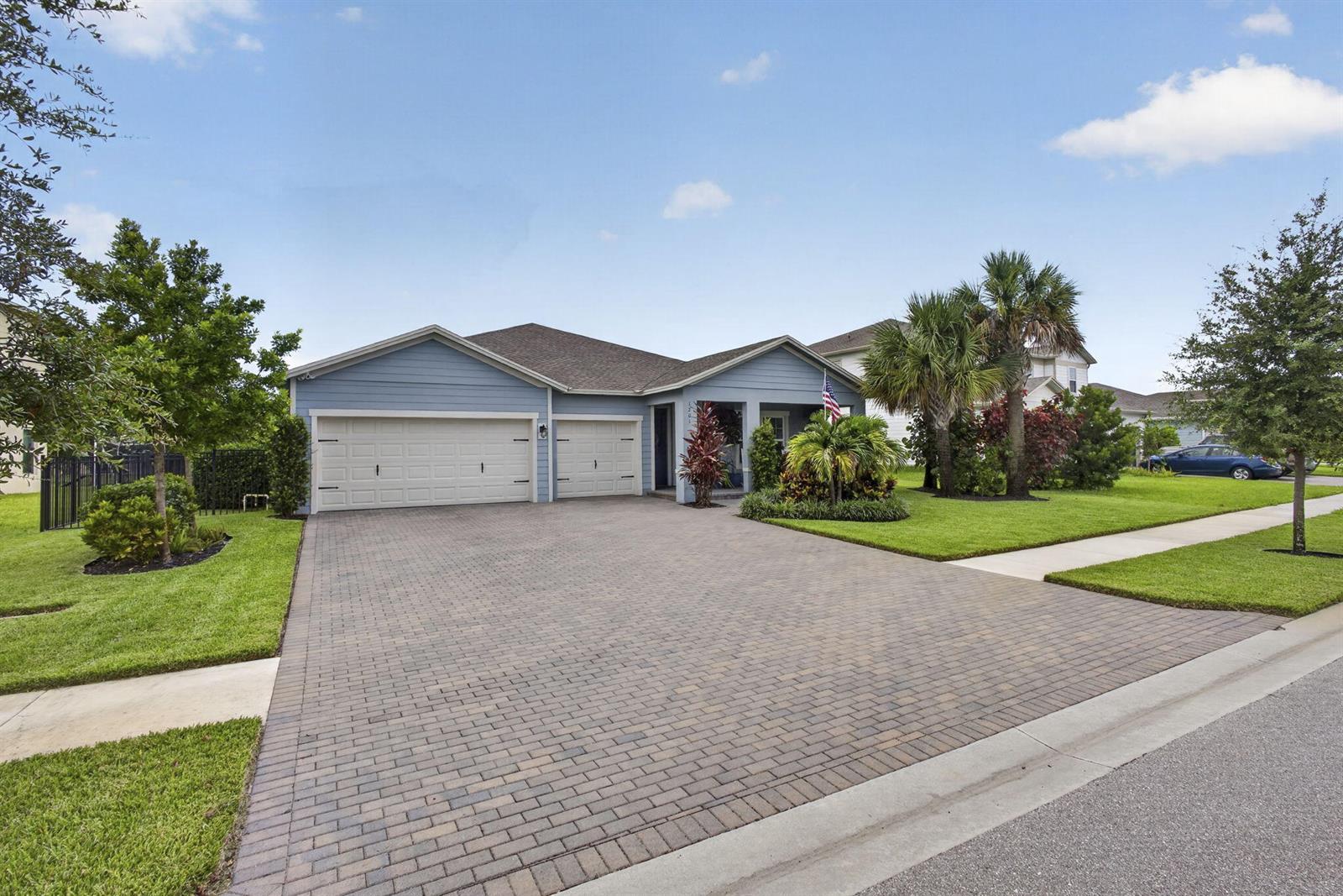 A blue single-story house with a brick paver driveway and a three-car garage — 1201 Harvester Crossing, Loxahatchee FL 33470, LOXAHATCHEE, FL
