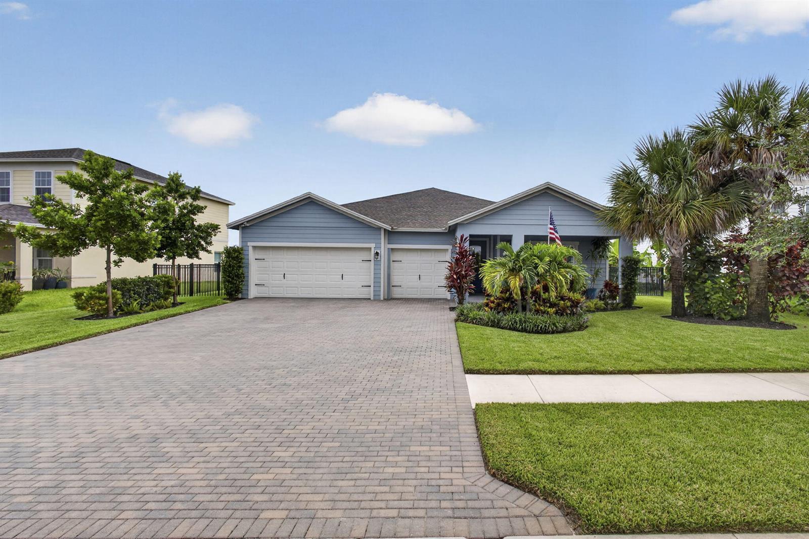 A blue single-story house with a three-car garage and a paved driveway — 1201 Harvester Crossing, Loxahatchee FL 33470, LOXAHATCHEE, FL