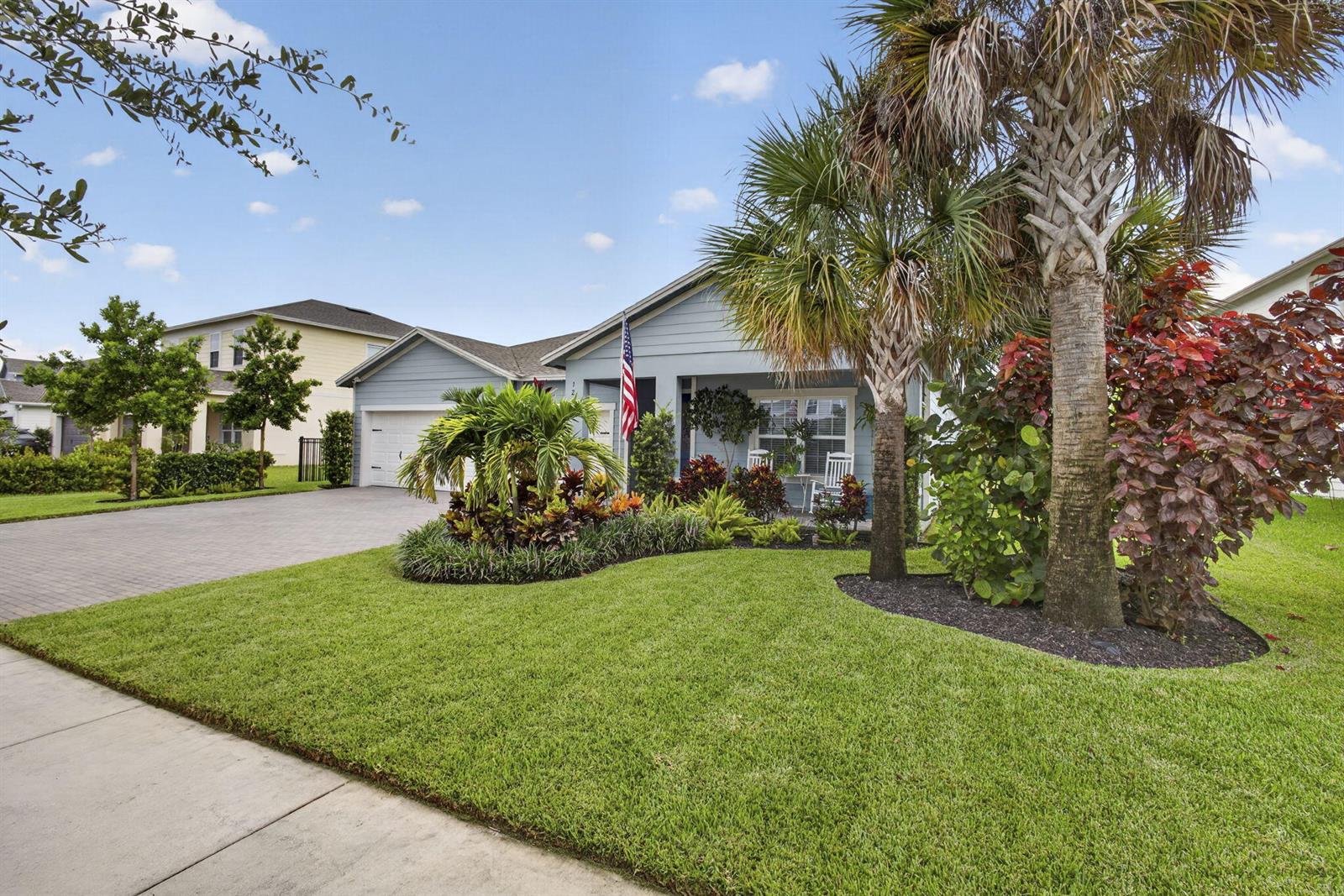 A light blue single-story house features a paved driveway, a front porch, and palm trees — 1201 Harvester Crossing, Loxahatchee FL 33470, LOXAHATCHEE, FL