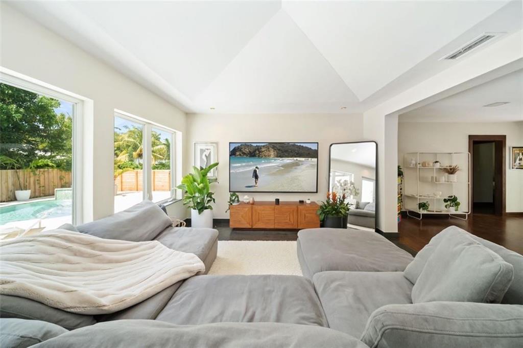 A living room features a large sectional sofa, a wall-mounted television, and floor-to-ceiling windows — 551 NE 53rd Street, Miami FL 33137, MIAMI, FL