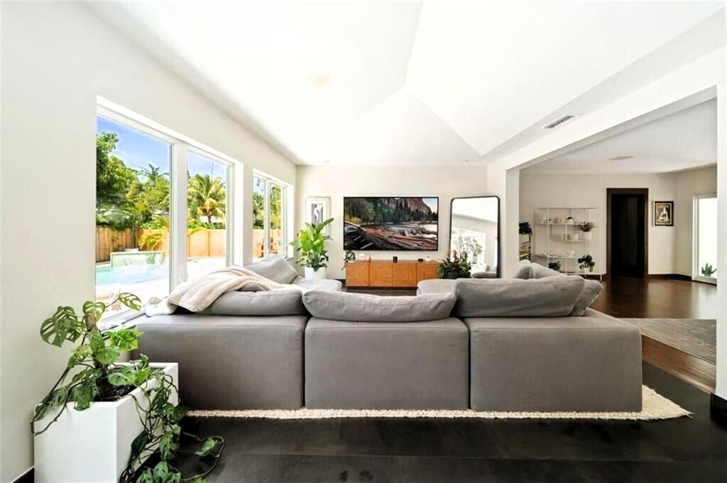 A living room features a large gray sectional sofa, vaulted ceilings, and floor-to-ceiling windows — 551 NE 53rd Street, Miami FL 33137, MIAMI, FL