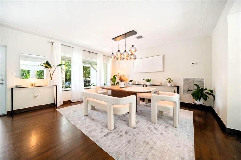 A dining room features a wooden table, white upholstered benches, and a modern globe chandelier — 551 NE 53rd Street, Miami FL 33137, MIAMI, FL