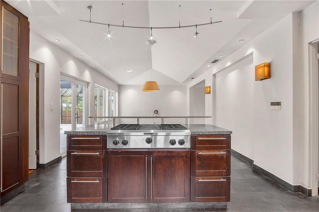A kitchen island with a stainless steel cooktop sits in a room with vaulted ceilings — 551 NE 53rd Street, Miami FL 33137, MIAMI, FL